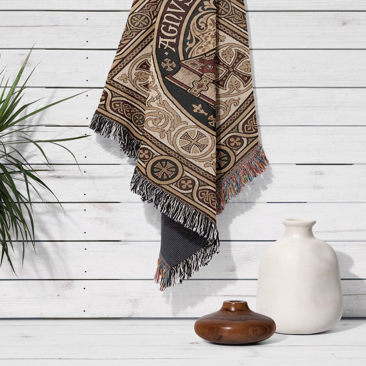Tapestry with intricate design and fringe hanging on white wooden wall.