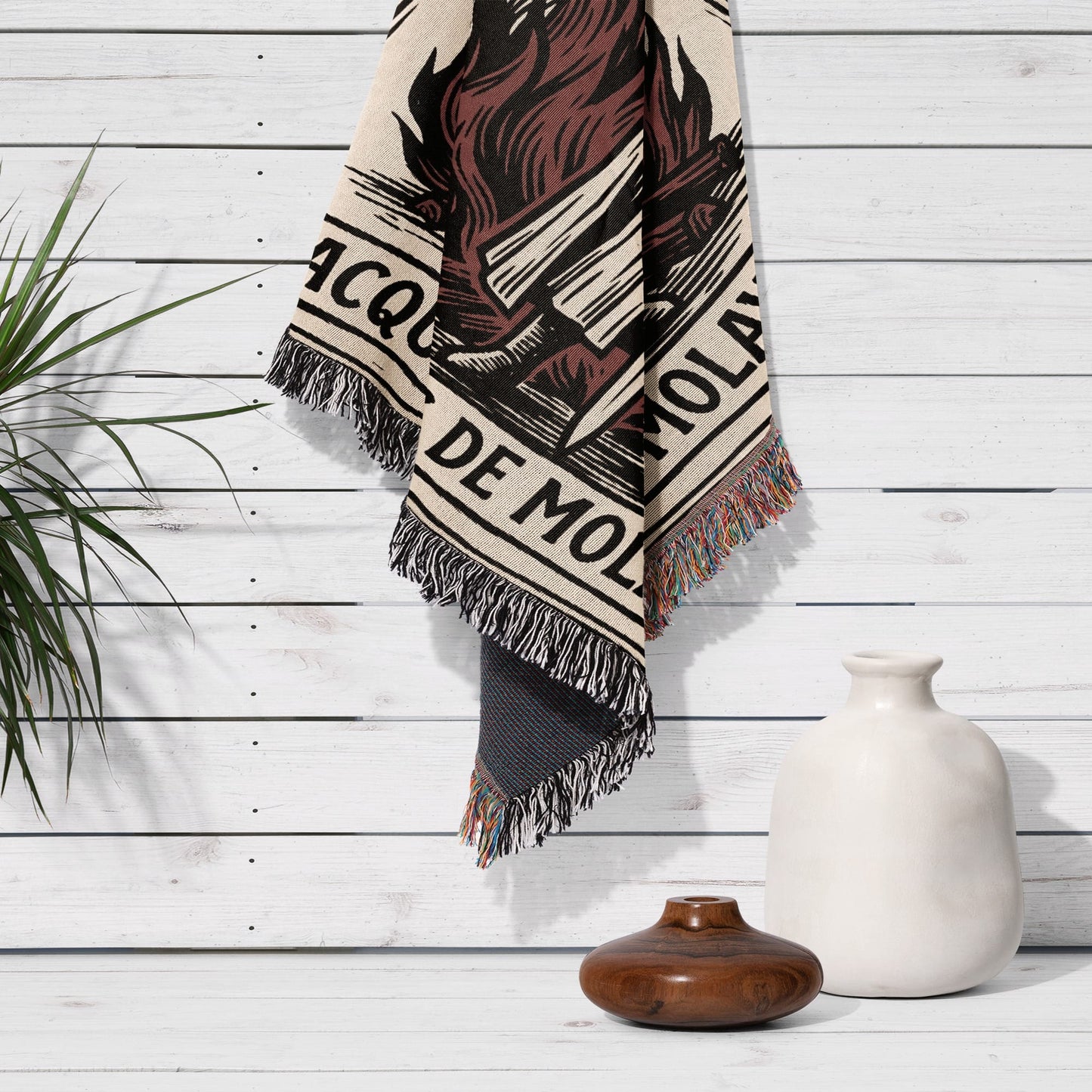 Woven tapestry with "Jacquemo" text, hanging on a white wood paneled wall.