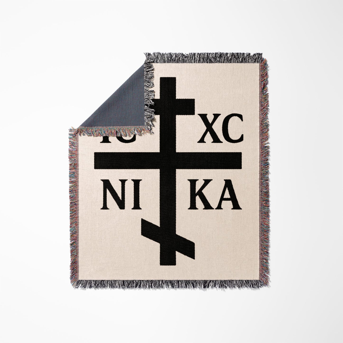 Black Orthodox Christian cross with Greek letters IC XC NIKA on a cream blanket.