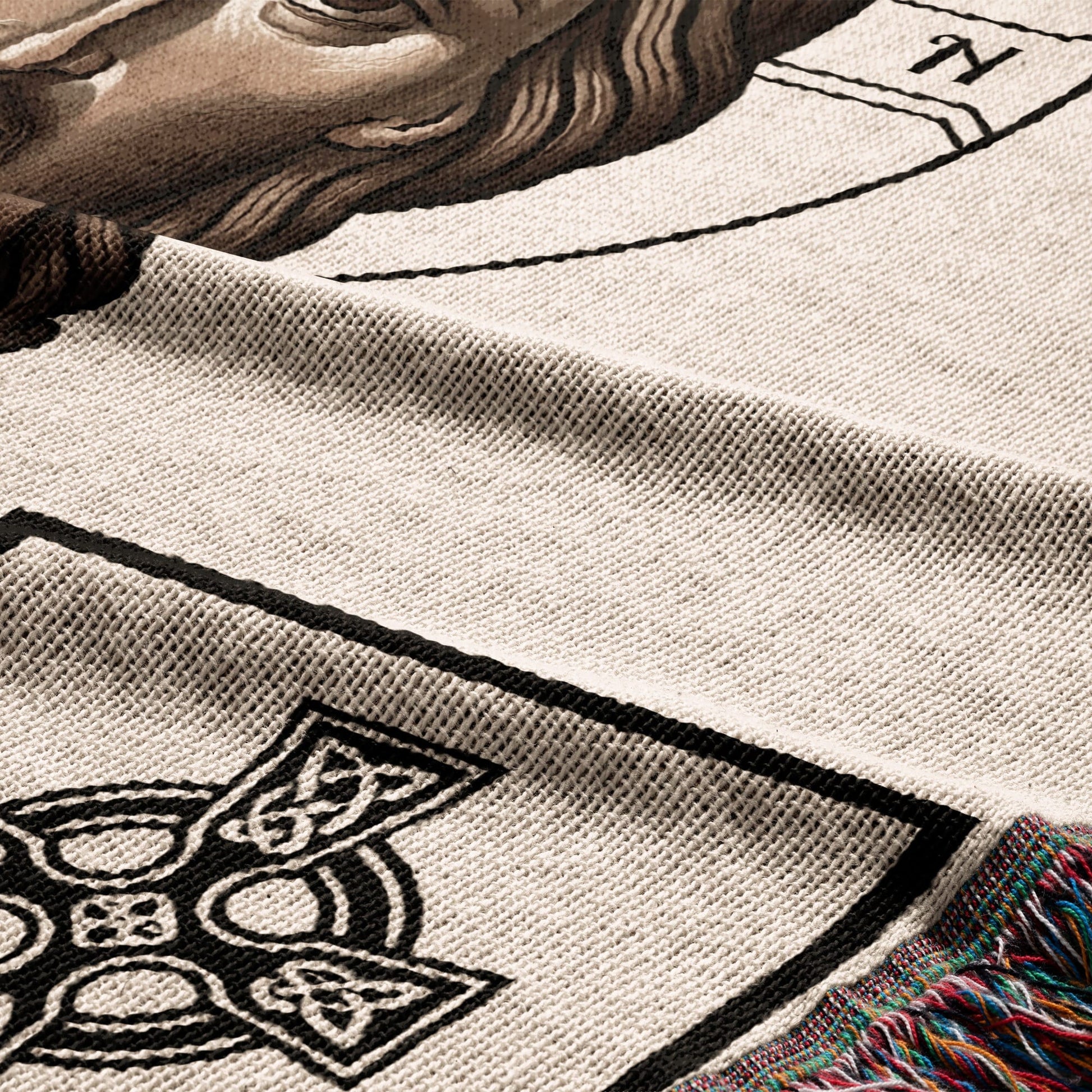 Cream knit blanket with Celtic knot detail and colorful fringe.