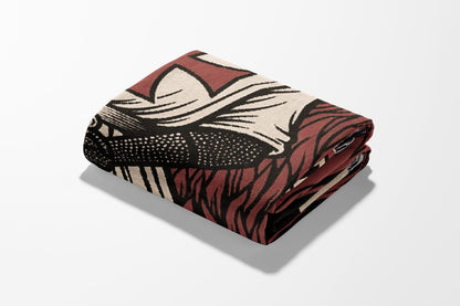 Folded blanket with a dark brown and tan geometric pattern.