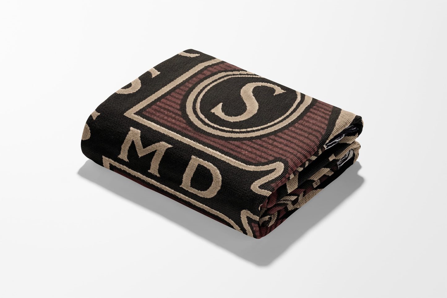Rolled blanket with dark background, beige and maroon letters and circular designs.