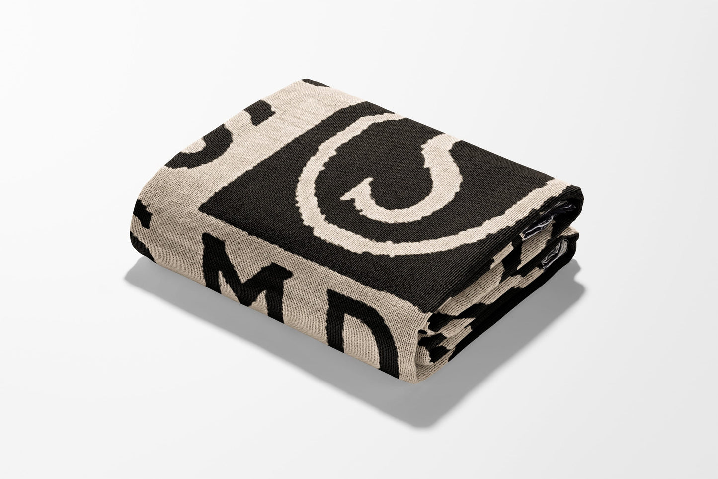 Rolled blanket with beige and black abstract pattern and visible text.