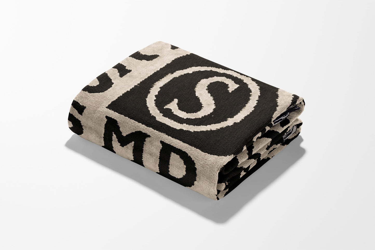 Folded black and cream blanket with large 'S' and letters.