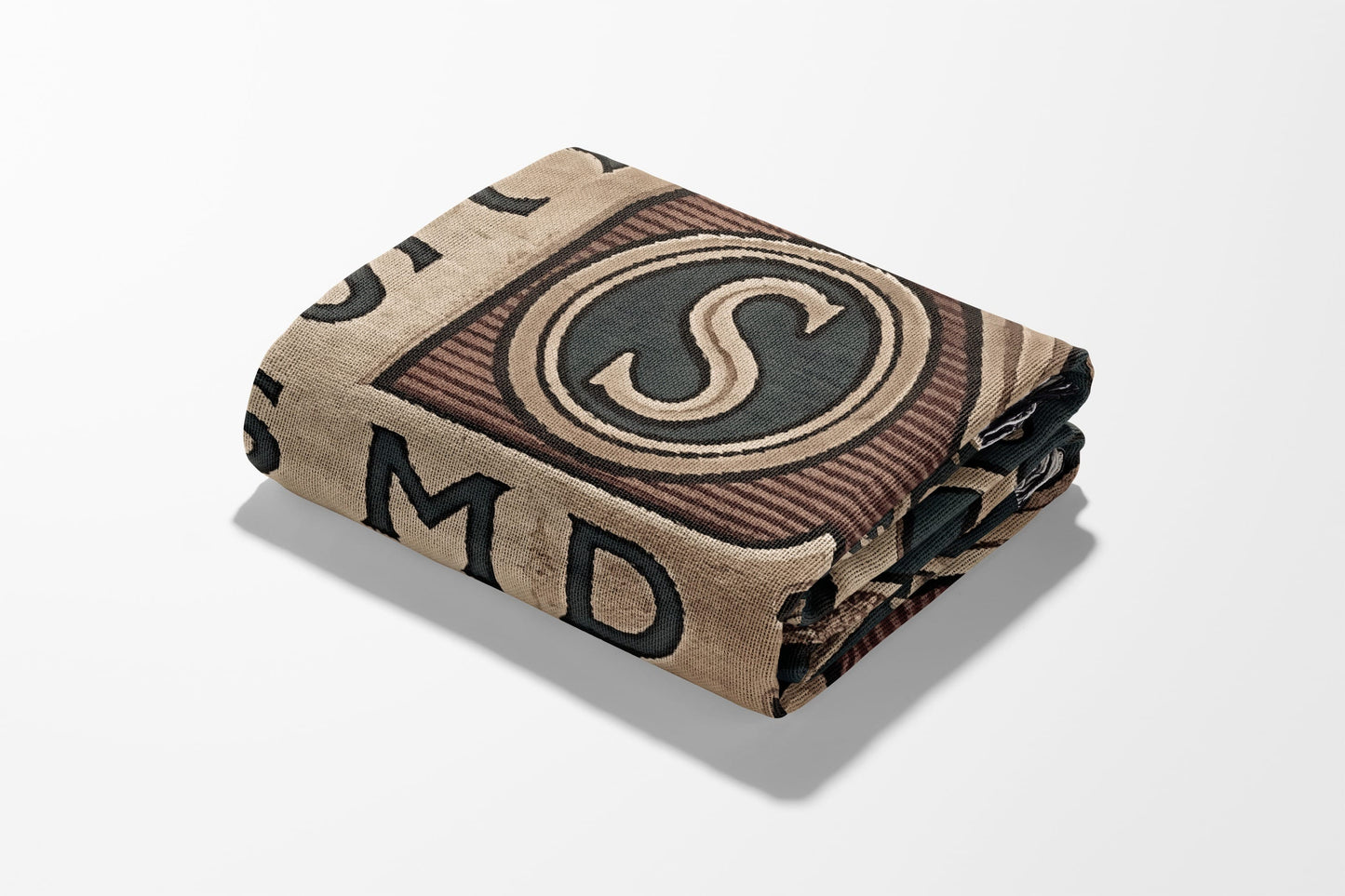 Tweed-style folded blanket with large letter "S" and visible text elements.