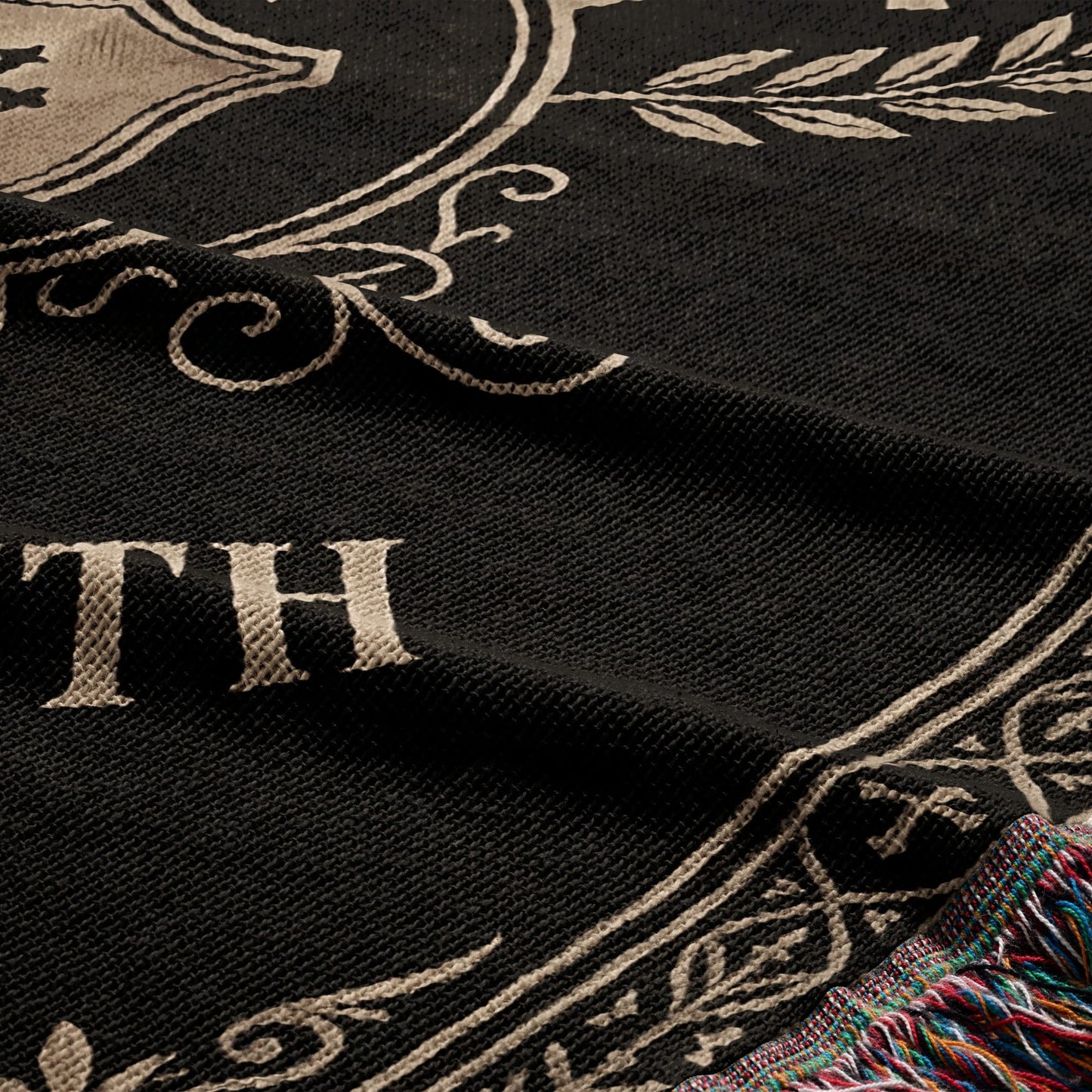Black blanket with tan text and ornate border, fringed edge.