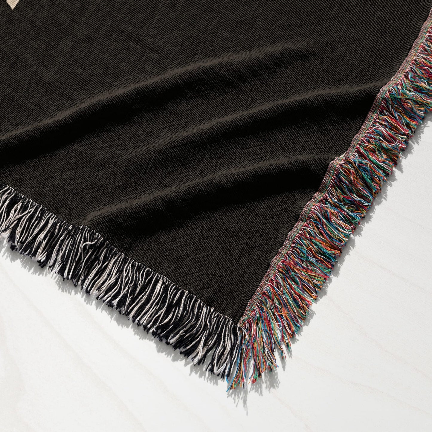 Black knit throw blanket with colorful fringed edges.