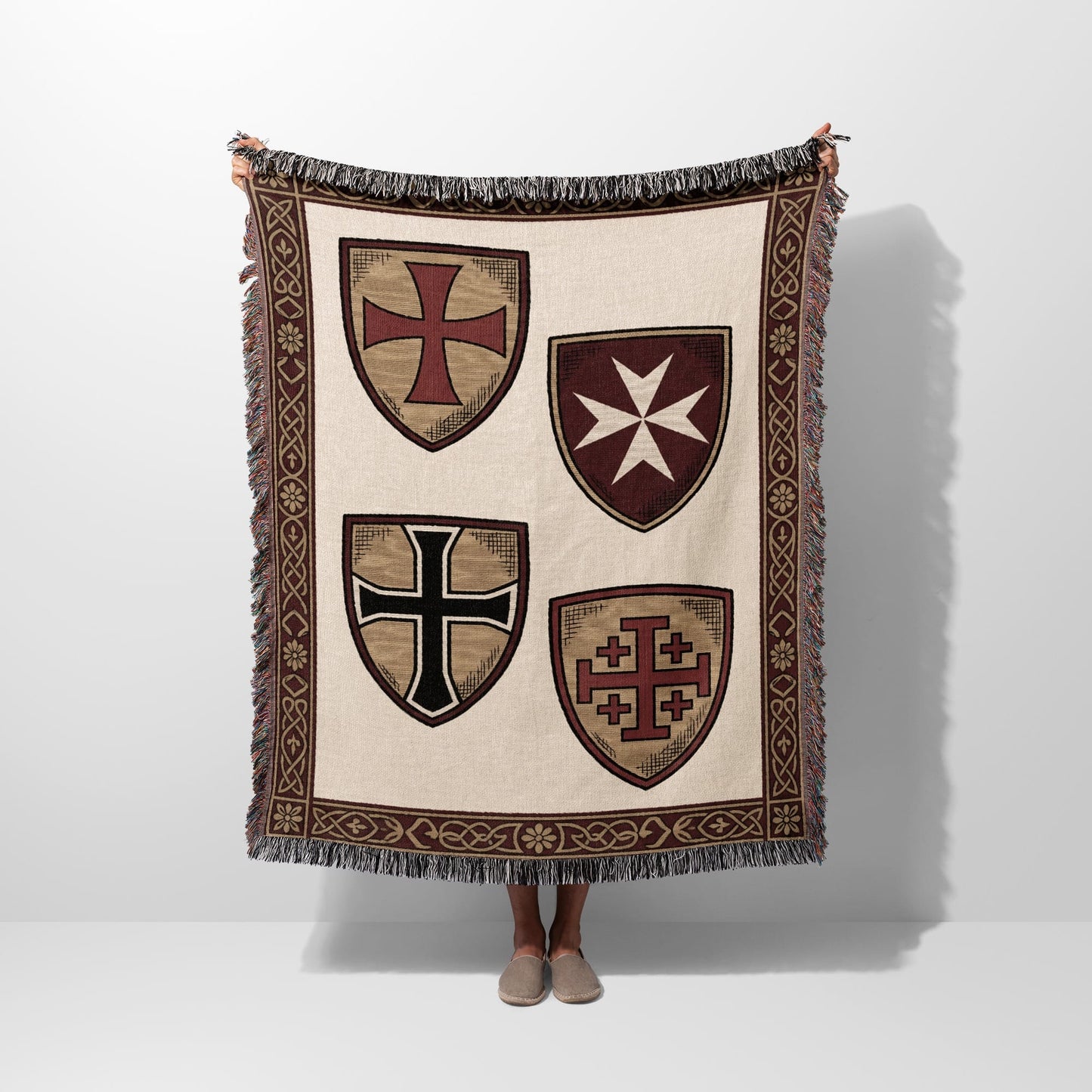 Beige throw blanket with four heraldic shields and patterned border.