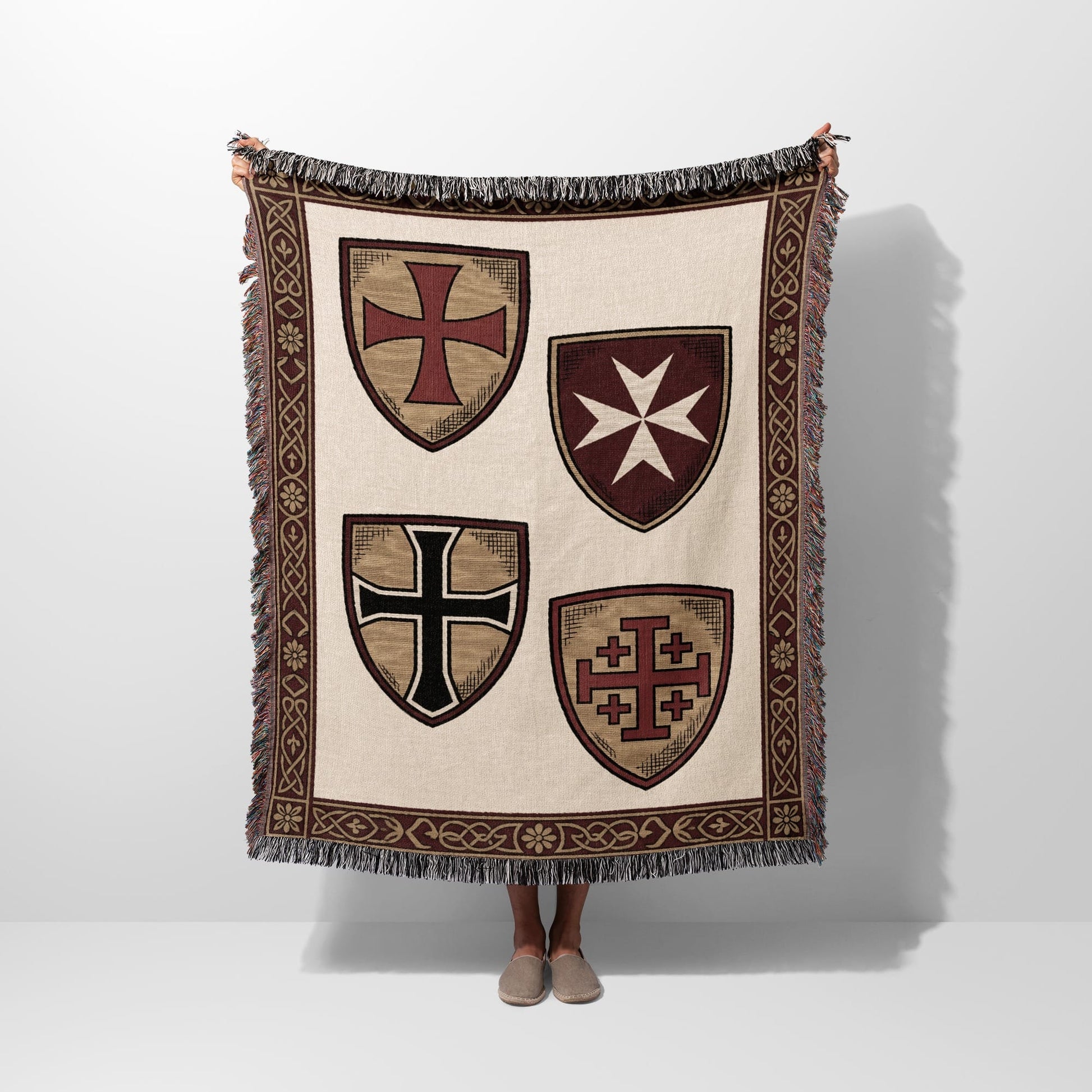Beige throw blanket with four heraldic shields and patterned border.