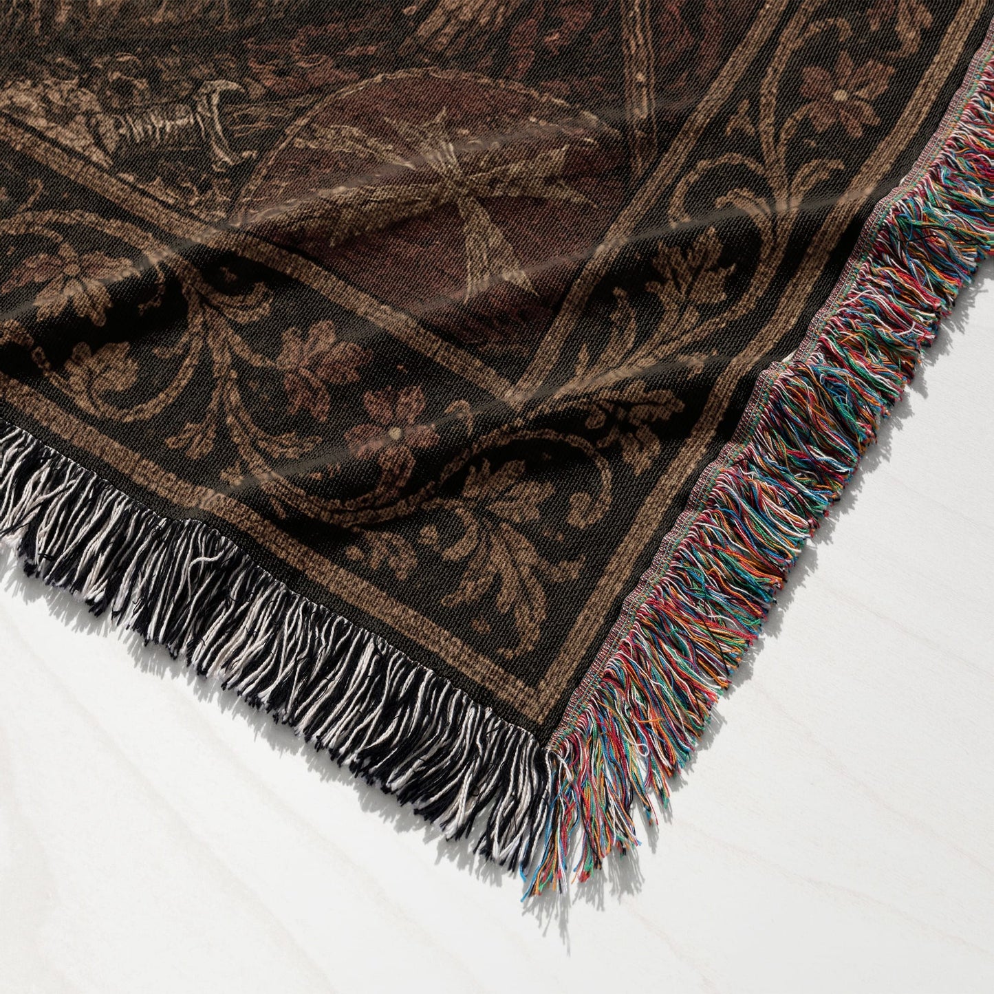 Dark brown woven blanket with fringe and intricate floral pattern.