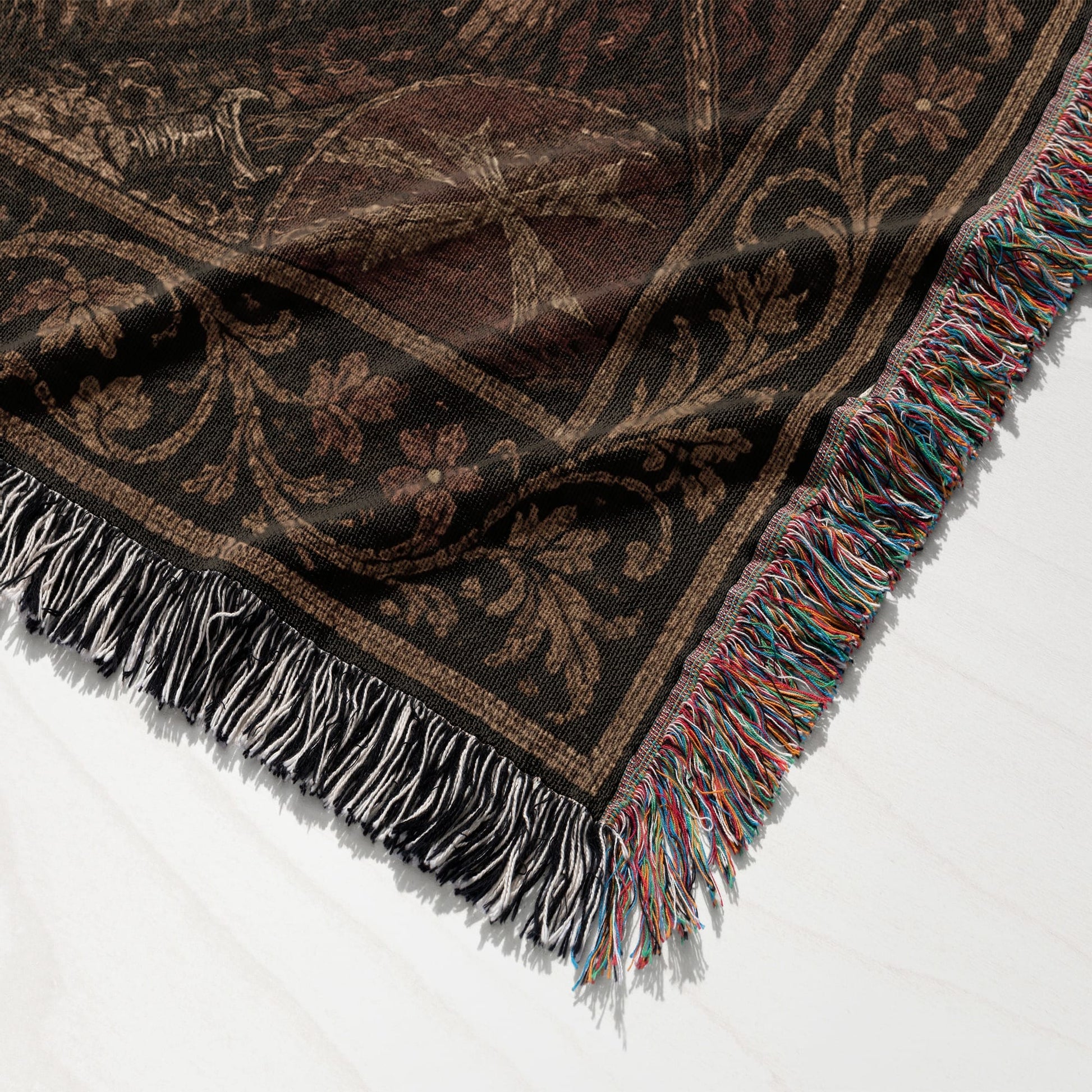 Dark brown woven blanket with fringe and intricate floral pattern.