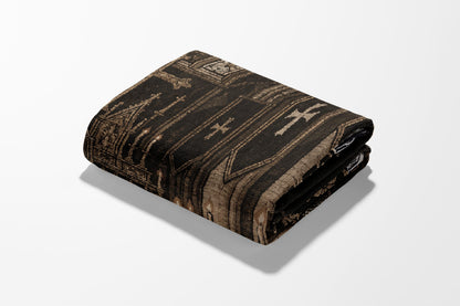 Folded dark patterned throw blanket with gothic-inspired design.