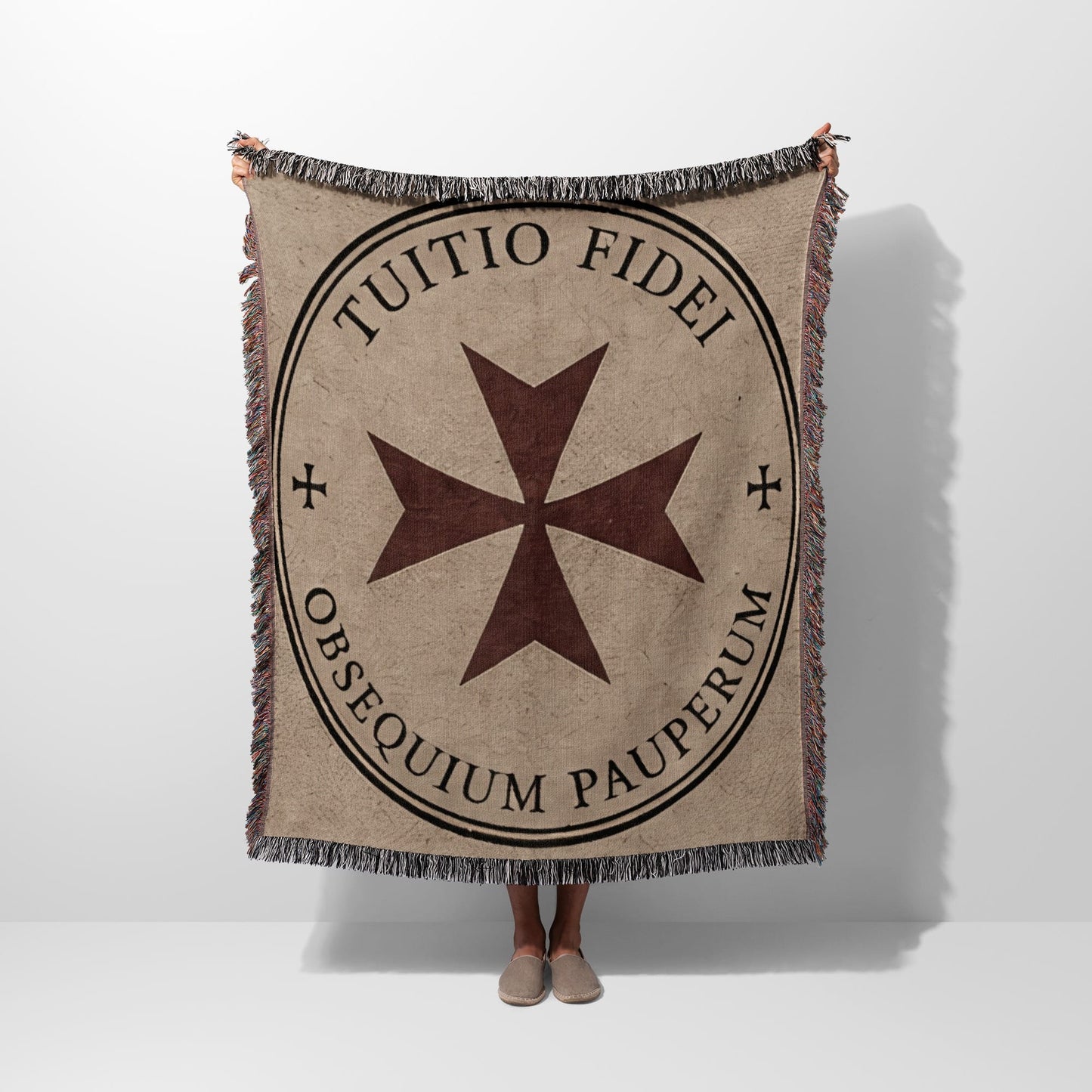 Beige woven blanket with a dark circle containing a Maltese cross and Latin text.