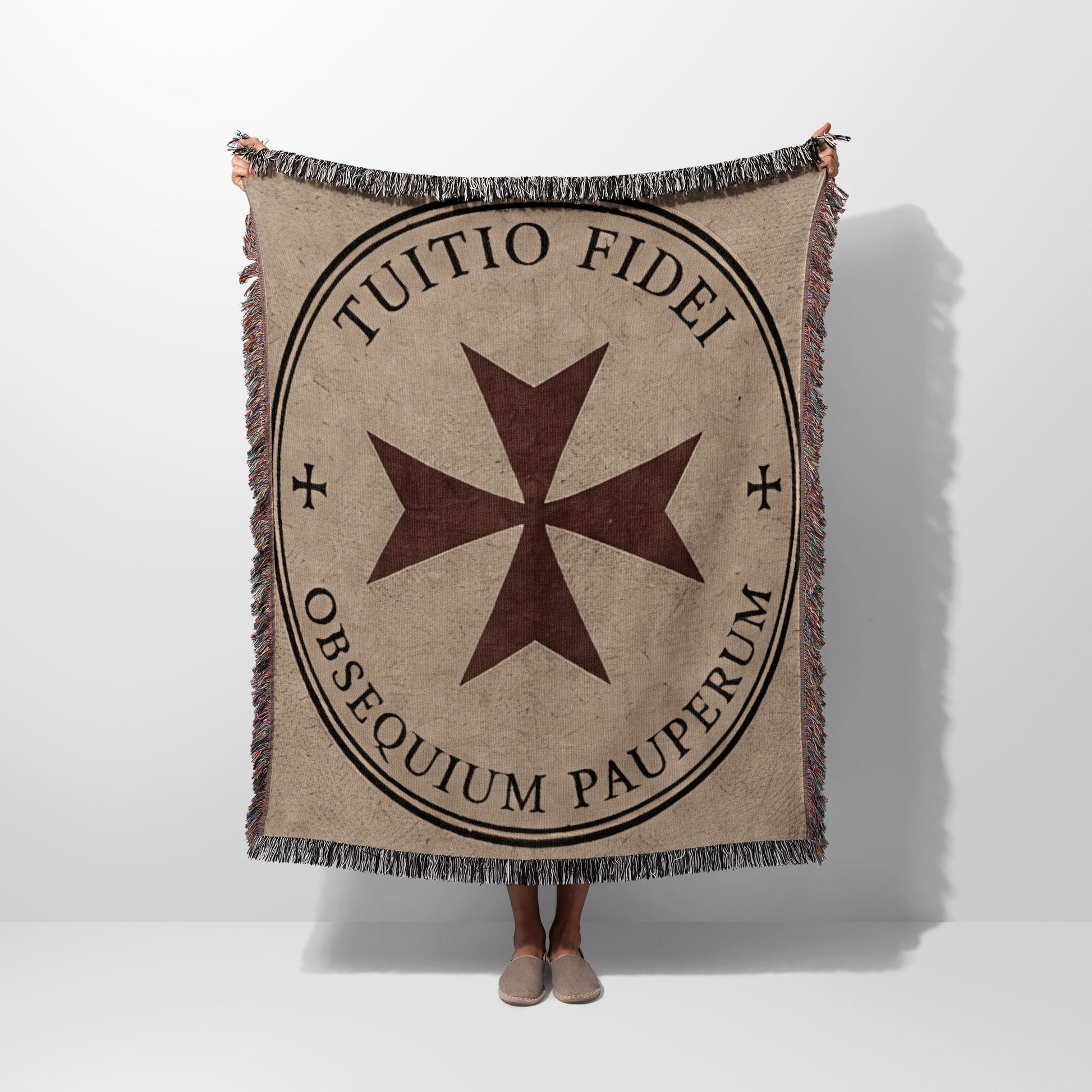 Beige woven blanket with a dark circle containing a Maltese cross and Latin text.