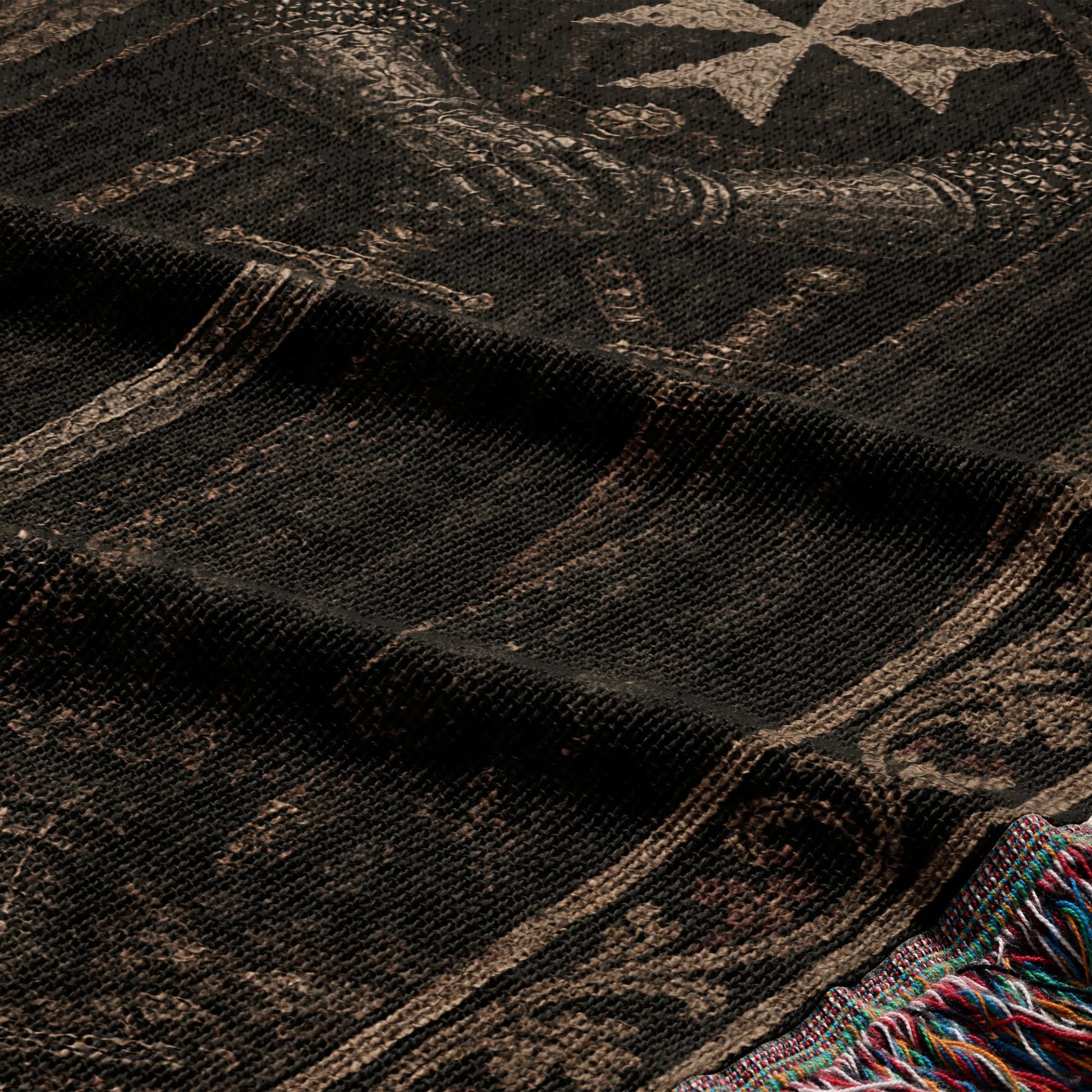 Black woven fabric with intricate tan pattern and fringed edge.