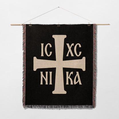 Black tapestry featuring a prominent cream-colored Orthodox Christian cross with text.