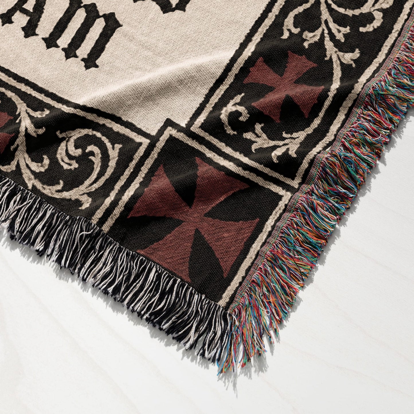 Woven blanket with Maltese crosses and intricate border, fringed edges.