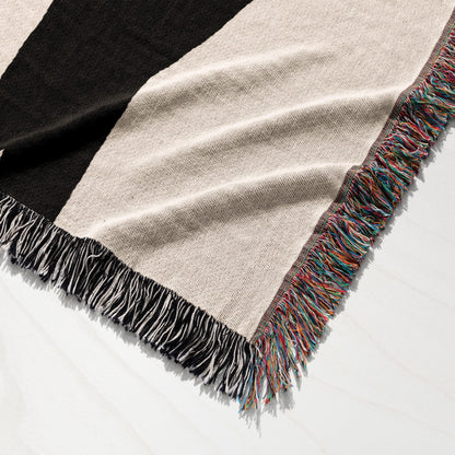 Black and beige striped throw blanket with colorful fringed edges.