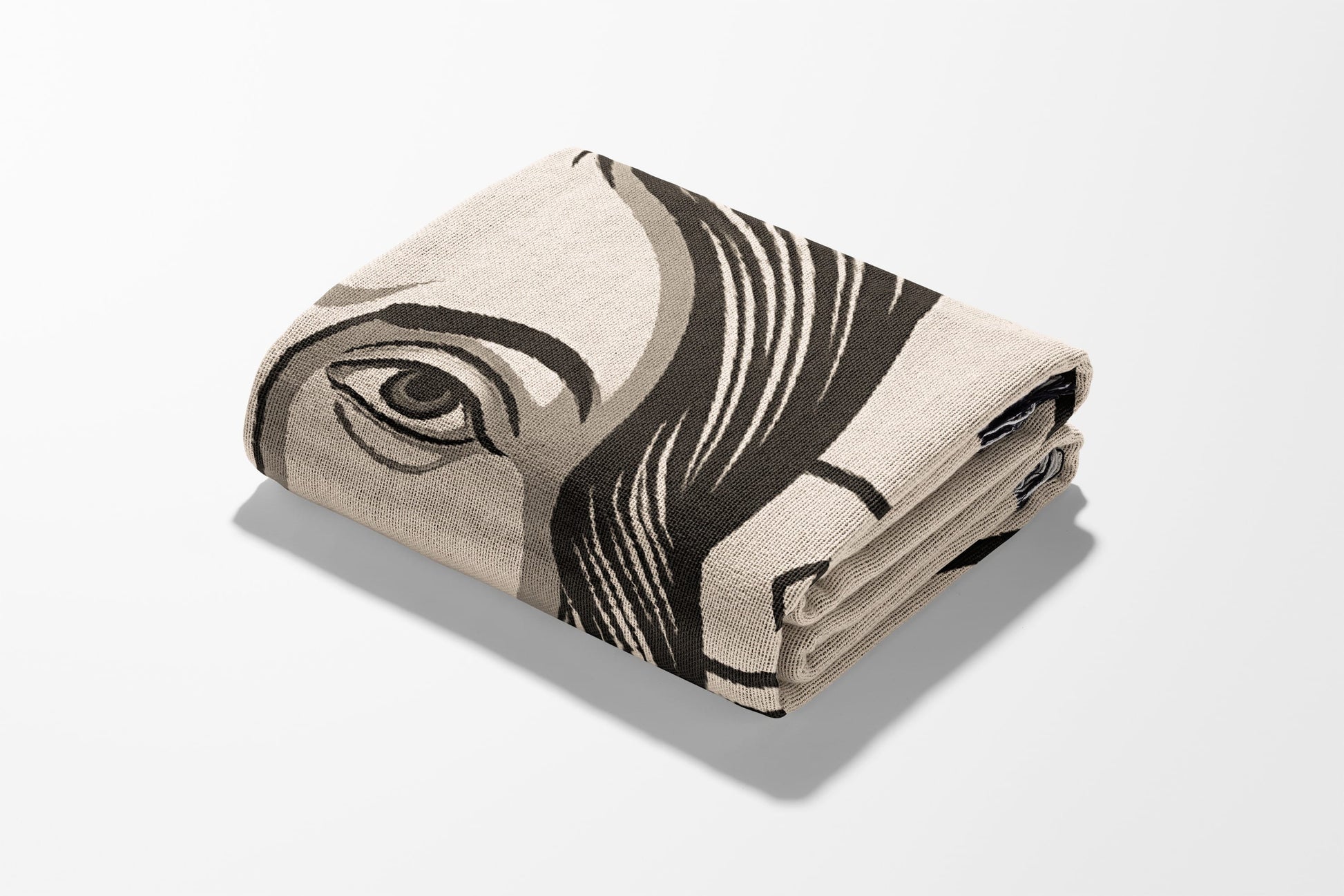 Folded blanket with abstract eye graphic design in beige and black.