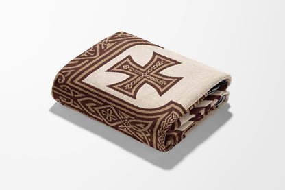 Folded throw blanket with a large Celtic knot cross and geometric border.
