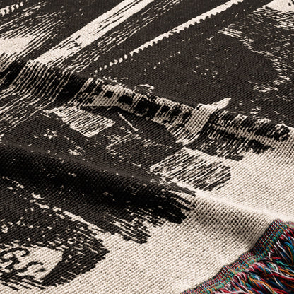 Woven blanket with abstract black and white pattern and fringed edges.