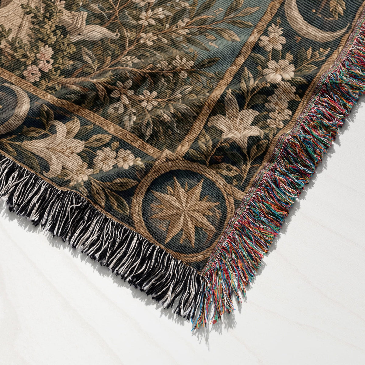 A woven throw blanket featuring a botanical illustration with celestial motifs and colorful fringed edges.