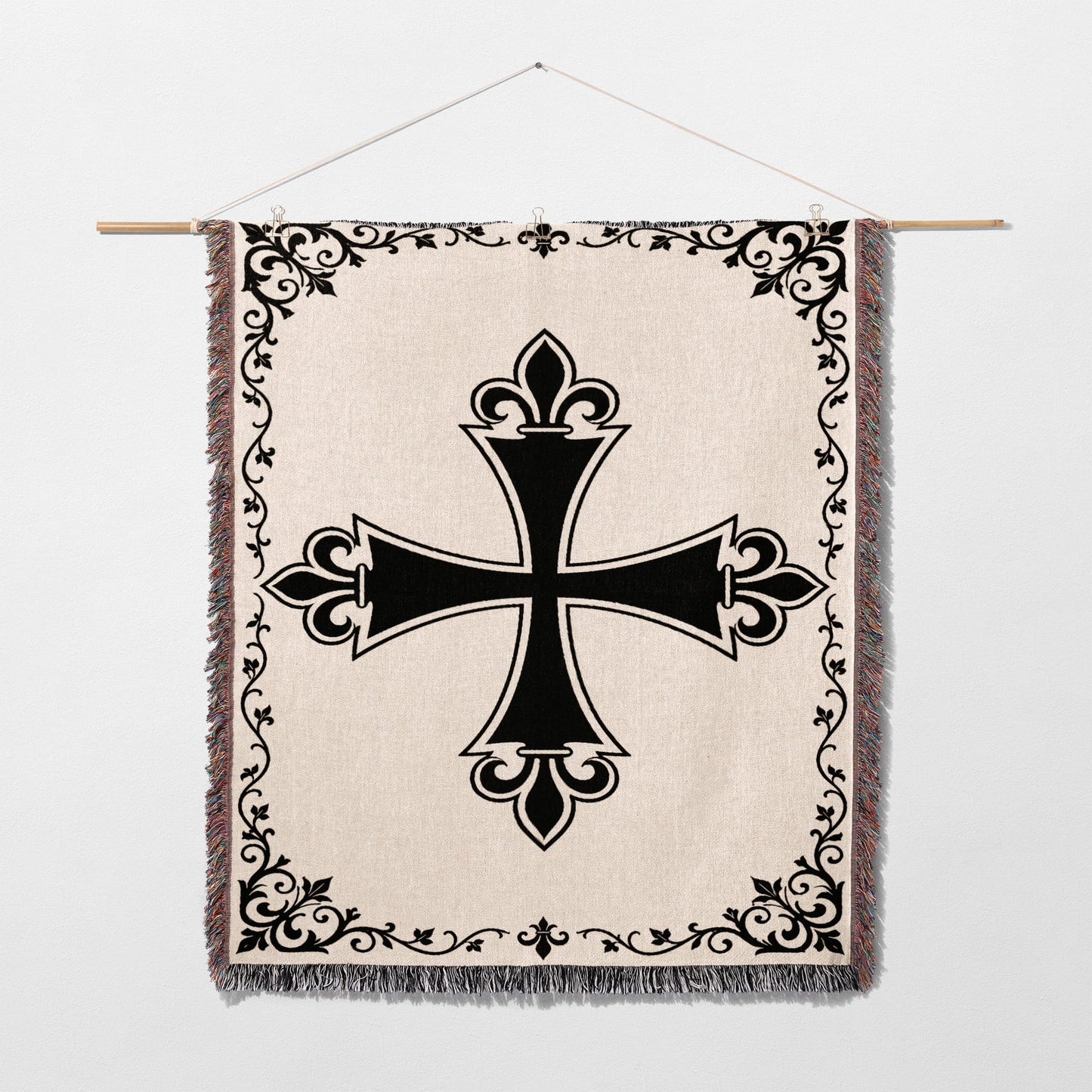 Black ornate cross on a cream tapestry with fringe and decorative border.