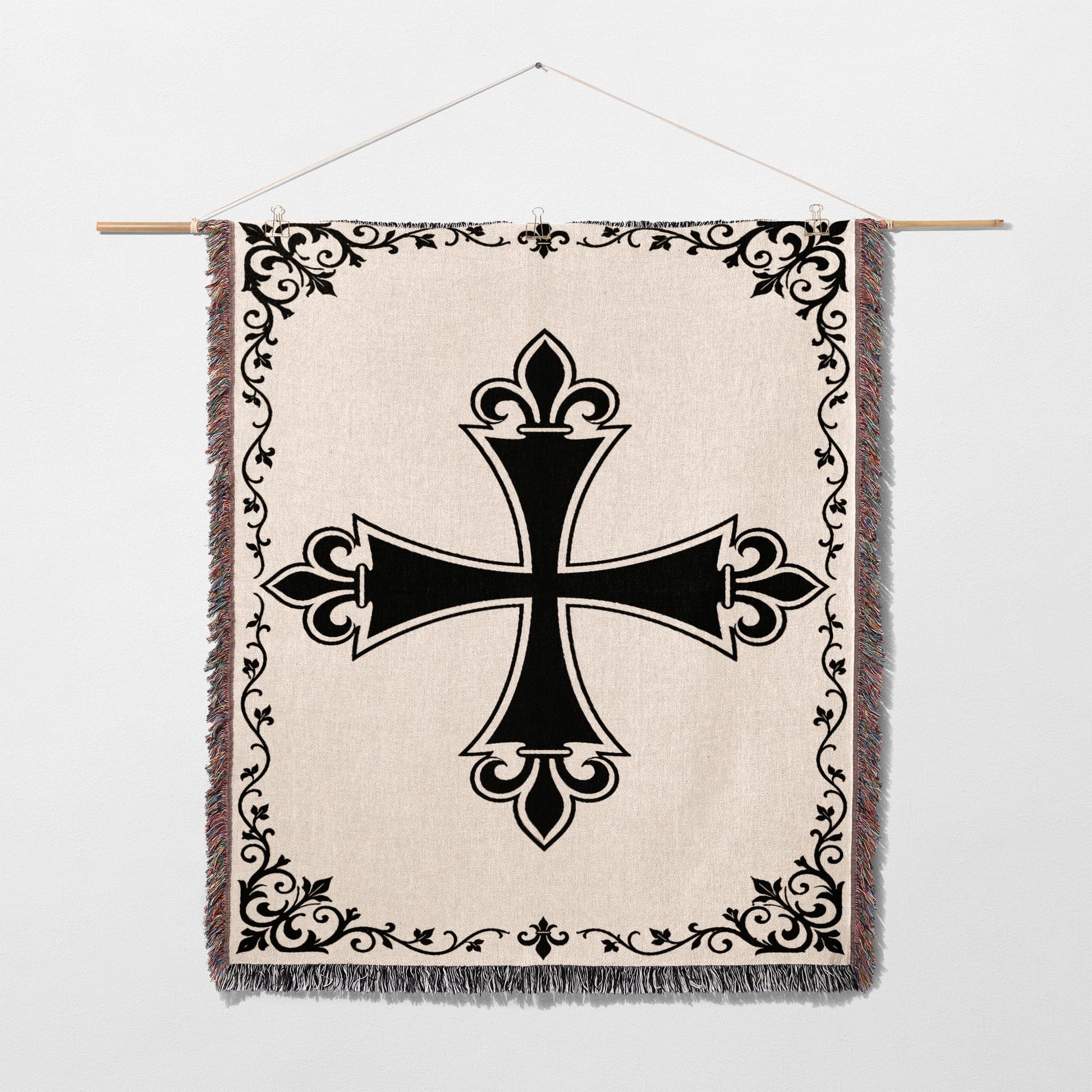 Black ornate cross on a cream tapestry with fringe and decorative border.