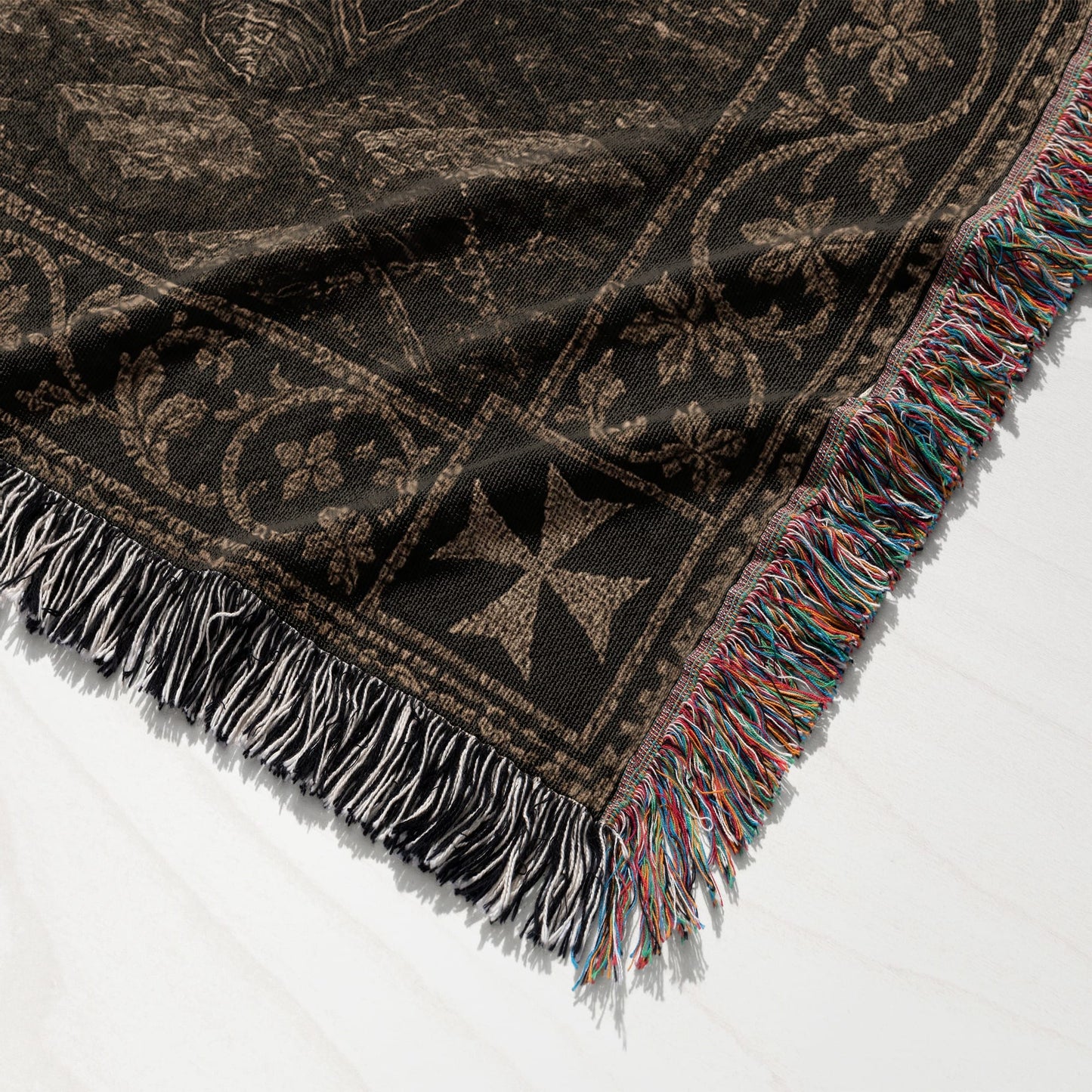 Brown woven blanket with fringe and ornate pattern.