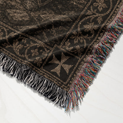 Brown woven blanket with fringe and ornate pattern.