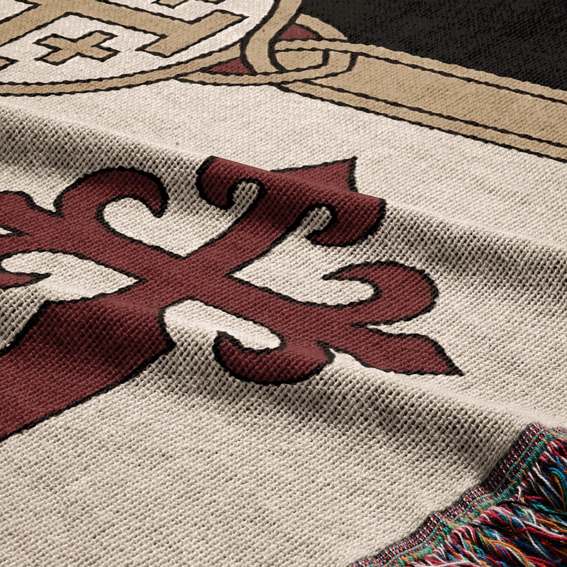 Cream woven blanket with a red stylized cross and fringed edge.