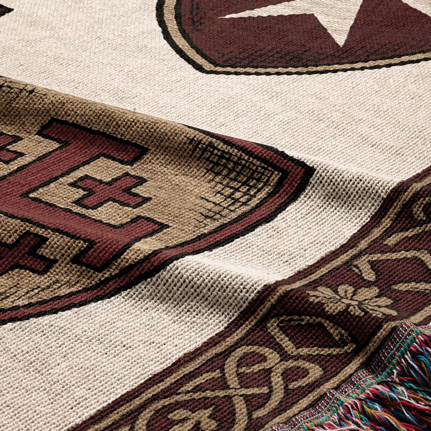 Woven tapestry blanket with a star, stylized E, and intricate border detail.