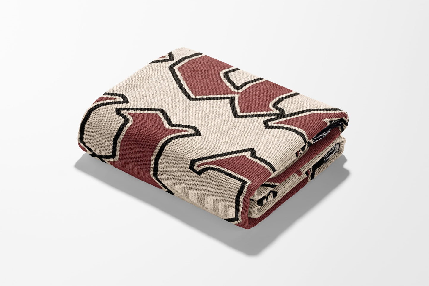 Folded tan blanket with a dark red geometric pattern.