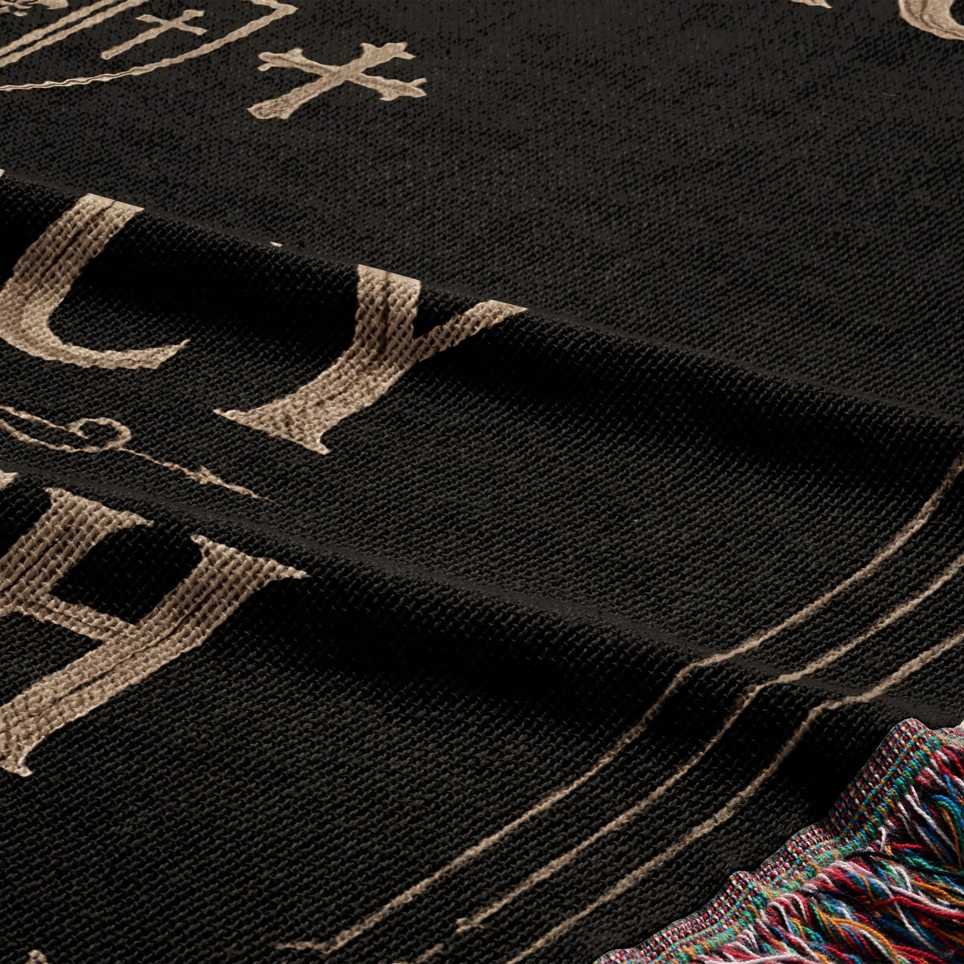 Black woven throw blanket with large tan letters and decorative border.