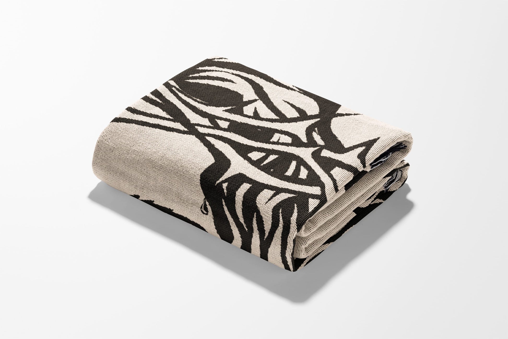 Folded blanket with black abstract design on cream background.