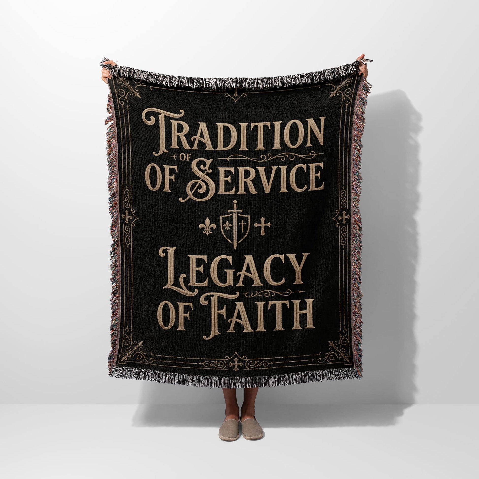 Black woven blanket with fringe, featuring text: Tradition of Service, Legacy of Faith.