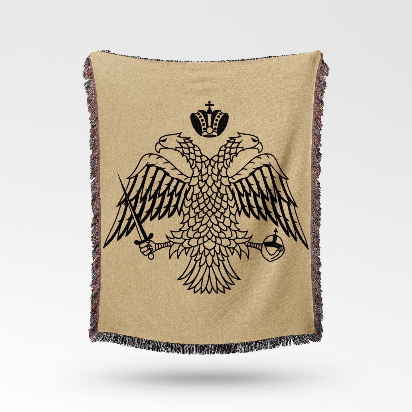 Black double-headed eagle crest on a tan woven blanket with fringed edges.