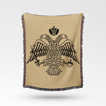 Black double-headed eagle crest on a tan woven blanket with fringed edges.