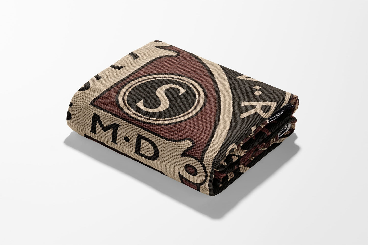 Folded blanket with a beige, maroon, and black pattern featuring the letter "S" and text.