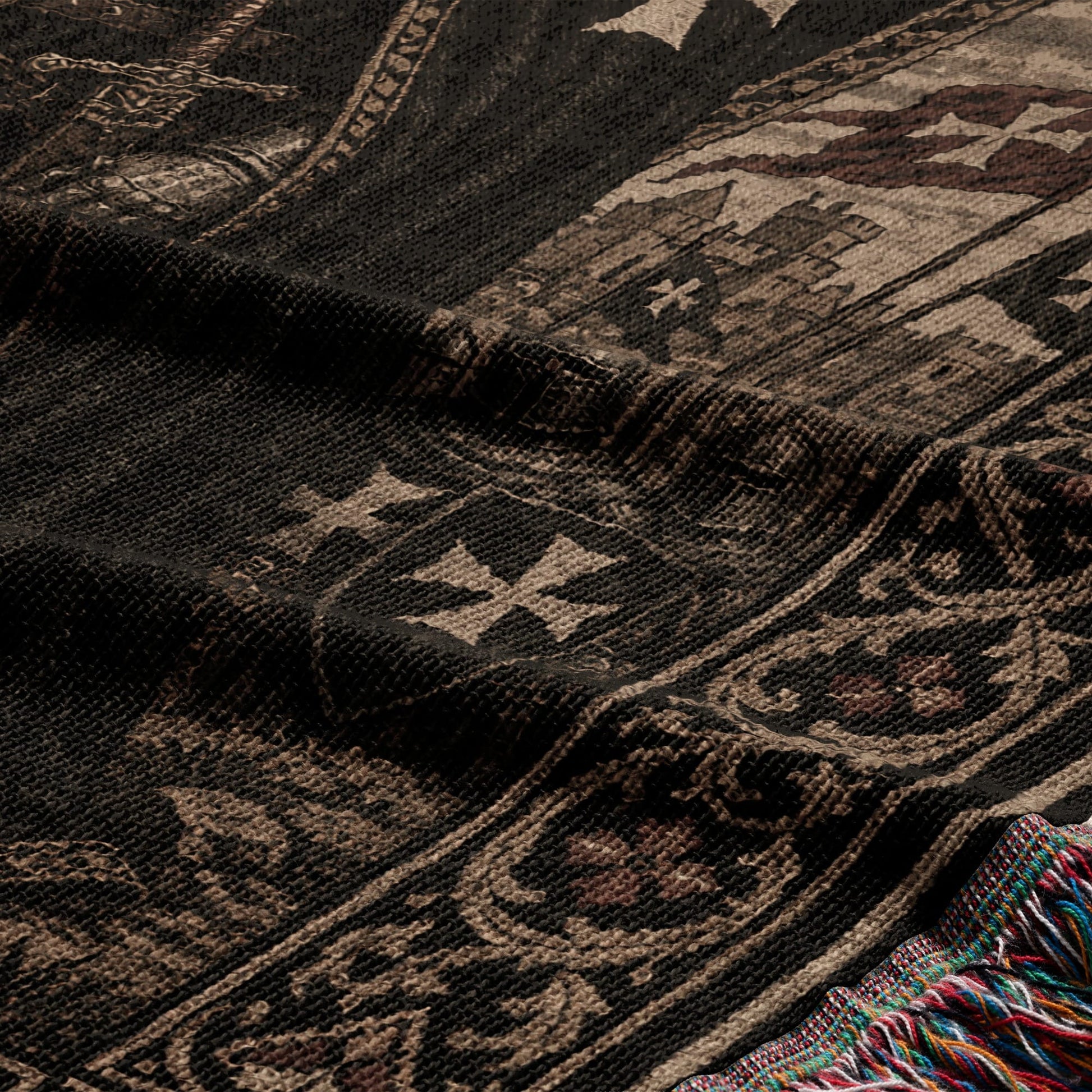 Dark woven fabric with ornate cross pattern and colorful fringed edge.
