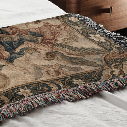 Woven throw blanket featuring a Renaissance art scene with winged figures, draped across a white bed.