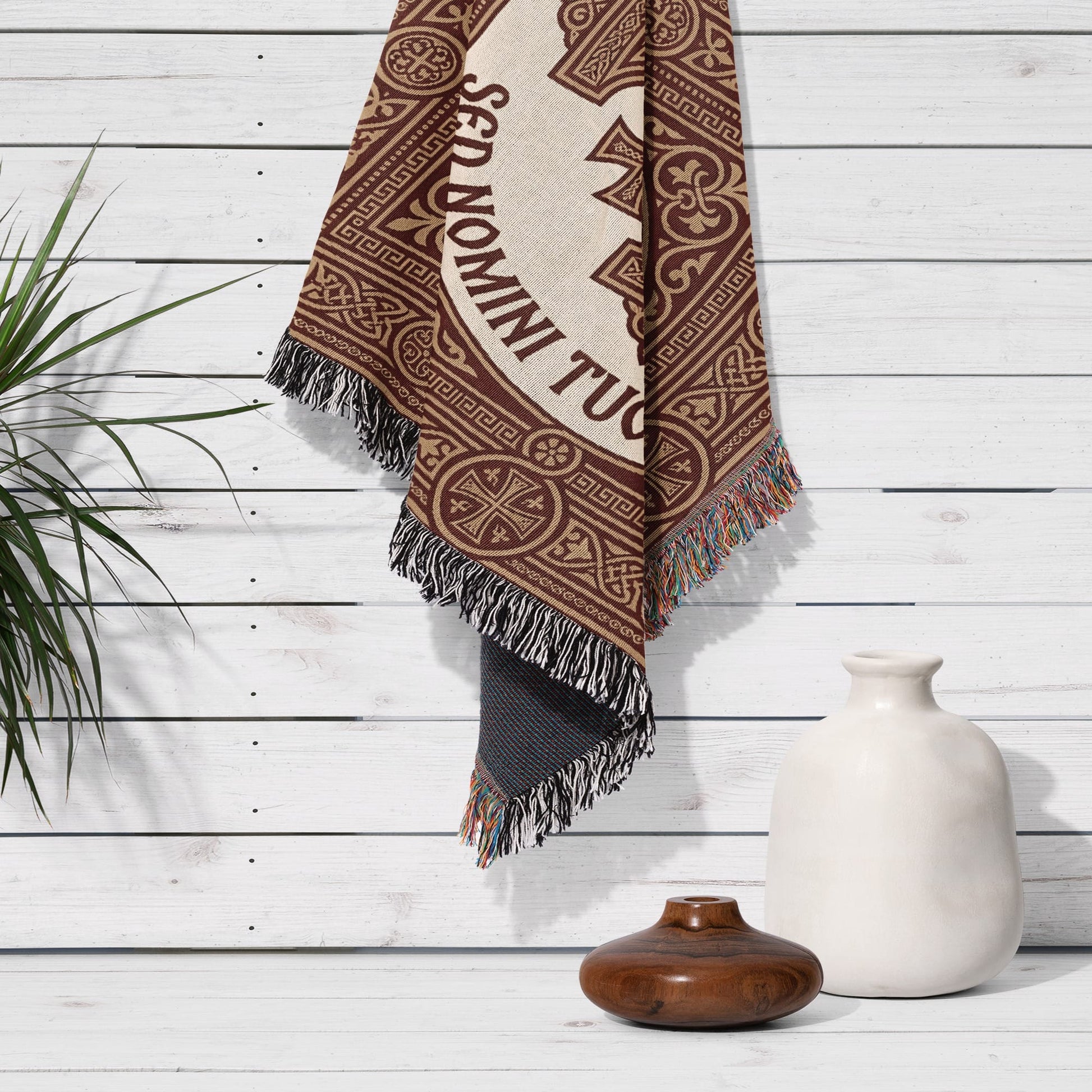 Brown and beige woven tapestry with "SED DOMINI TUA" text hanging on a white wall.