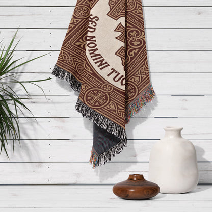 Brown and beige woven tapestry with "SED DOMINI TUA" text hanging on a white wall.