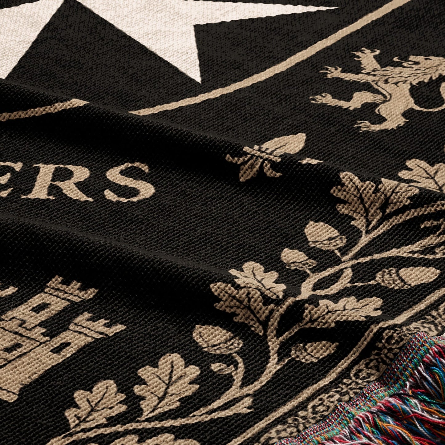 Black blanket with a tan lion, star, castle, and oak leaves pattern.