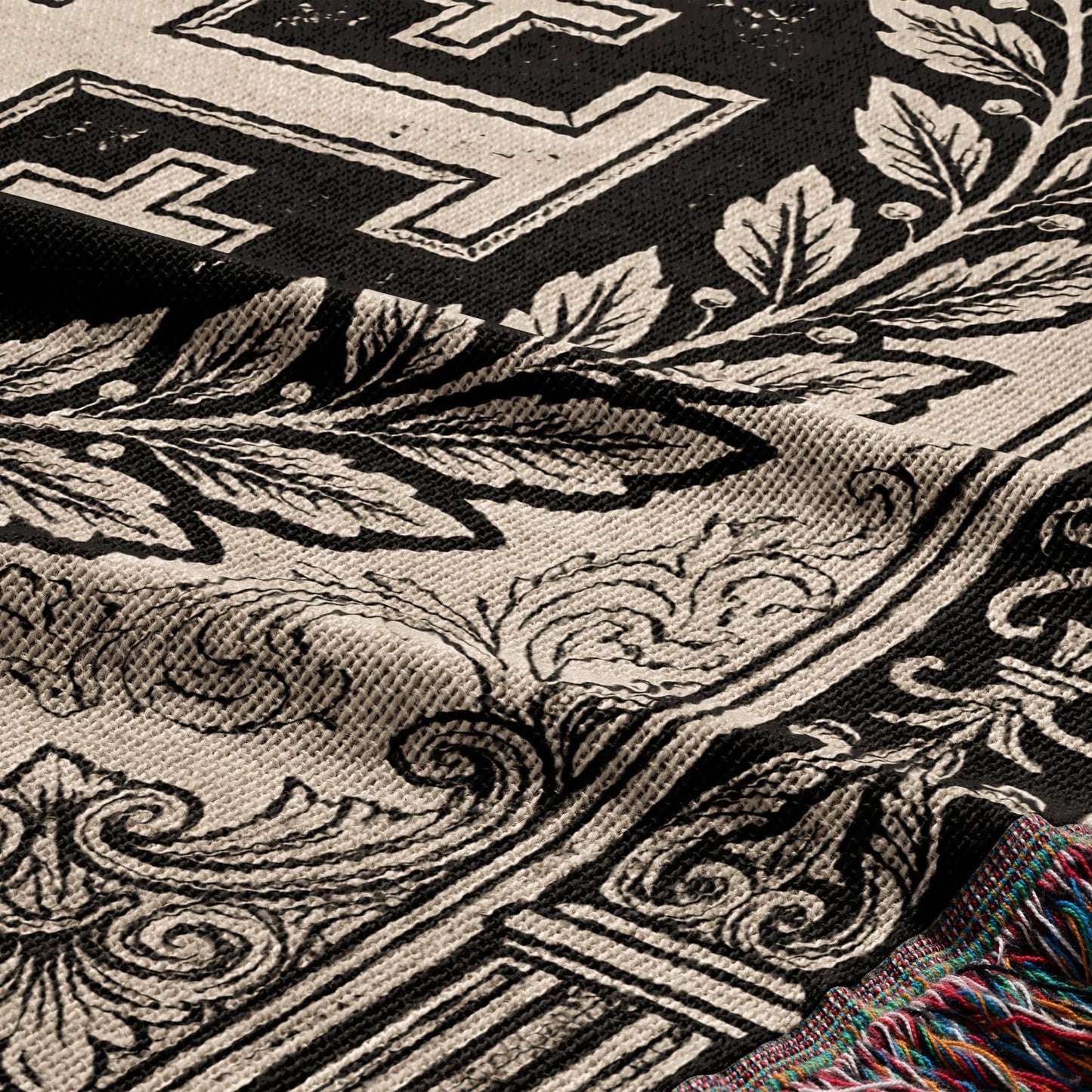 Tapestry with black and cream ornate scrolling leaf pattern and fringed edge.