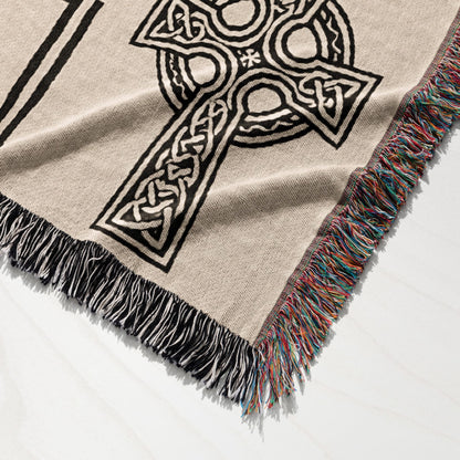 Woven throw blanket with Celtic knot cross design and fringed edges.