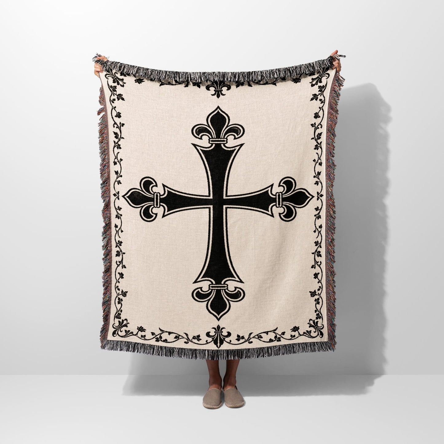 Cream woven blanket with black ornate cross and fringe.