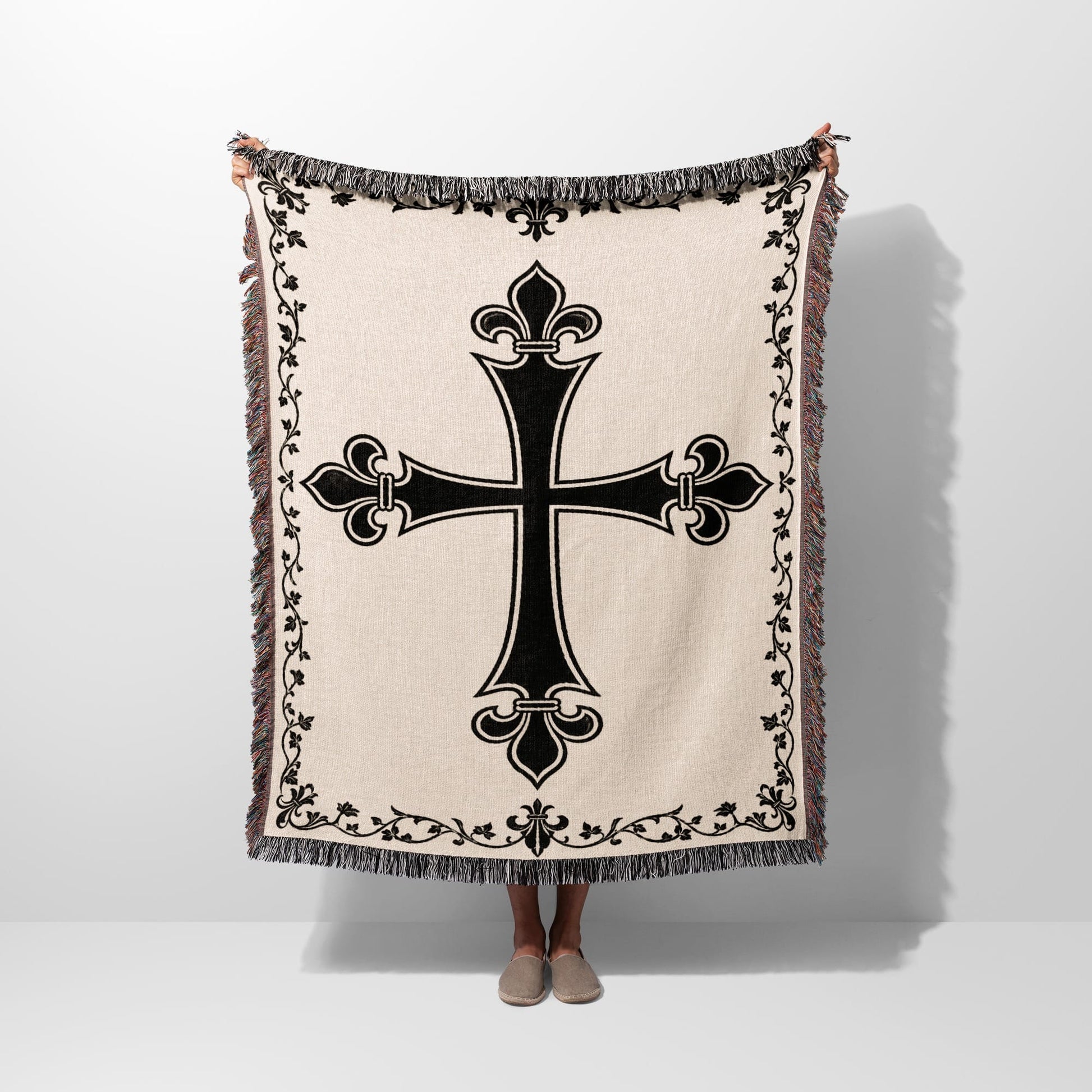 Cream woven blanket with black ornate cross and fringe.