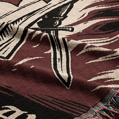 Close-up of a woven blanket with a sword and swirling patterns in red and black.