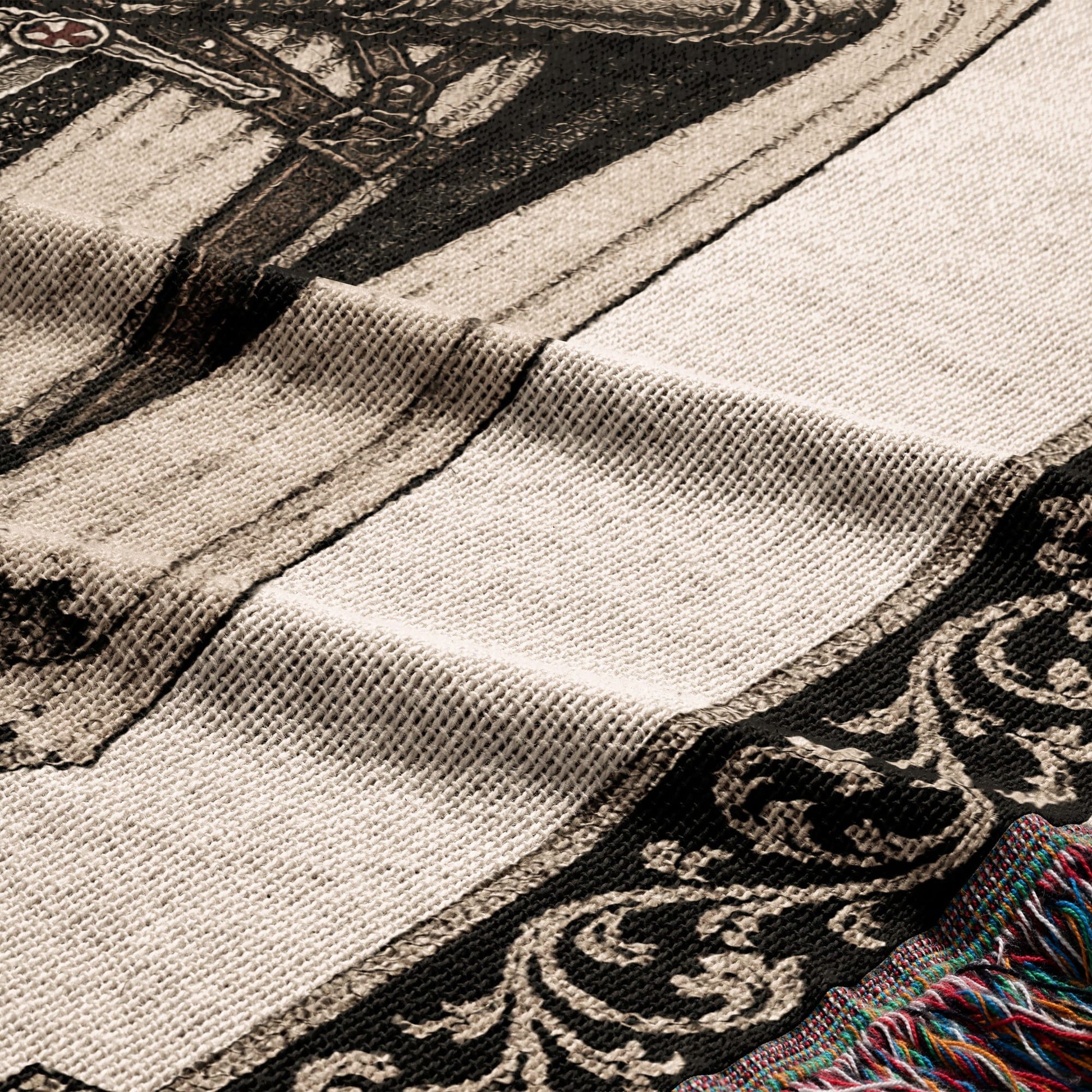 Textile with ornate dark pattern and cream stripes, fringed edge.